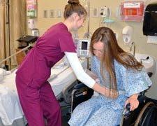Nursing Assistant helping female patient into wheelchair